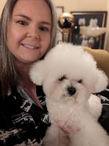 Mally the white Bichon Frise is held by his owner