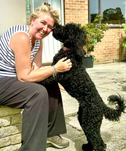 Indie the black Australian Labradoodle kisses her owner