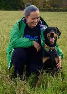 Gruto the black and tan Lithuanian Hound sits with his owner in the grass