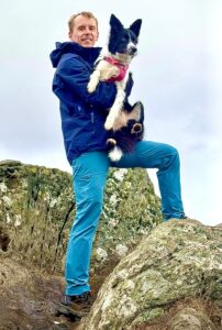 Toffee the black and white Border Collie is held by their owner