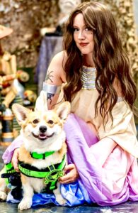 Tan and White Corgi posing with owner and wearing a green harness