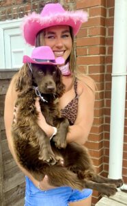 Chocolate Working Cocker Spaniel wearing a pink cowboy hat with her owner