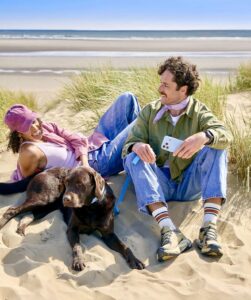 Chocolate Labrador laying on the beach with his human friends