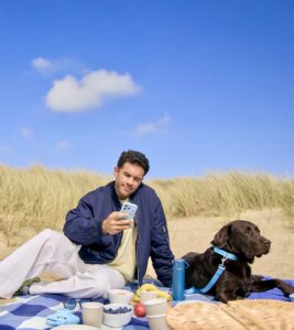 Chocolate Labrador sitting on the beach with his owner